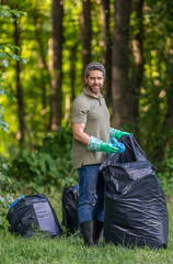 Man collecting plastic trash. Eco volunteer. Garbage collecting in forest. Ecology concept....