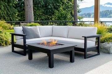Obraz premium Inviting outdoor patio with modern fire pit table and comfortable sofa overlooking serene lake and lush evergreen forest landscape