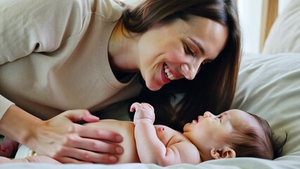 Happy mother lying next to her baby, smiling and playing in a cozy home environment. Concept of maternal love and family bonding.
