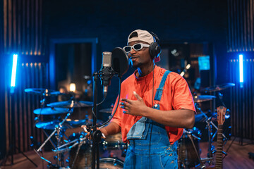 Young stylish singer recording new hit song in professional music studio