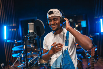 Young male artist recording music in professional studio
