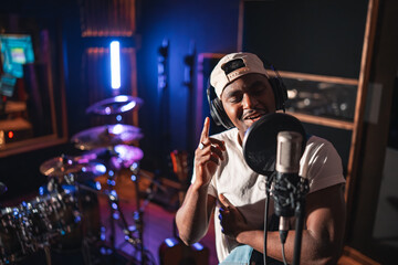 Young male singer recording new hit song in professional studio