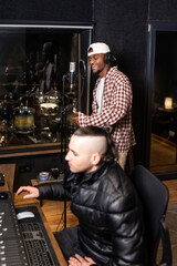 Singer recording new hit song with sound engineer in music studio