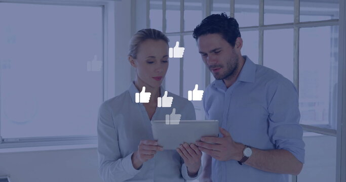 Image of digital thumbs up icons and data processing over diverse business people in office - Powered by Adobe