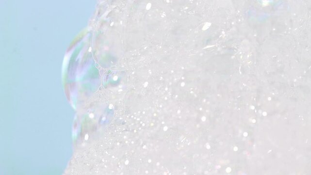 Small bubbles of cosmetic soap, shampoo flow down a vertical surface, front view.