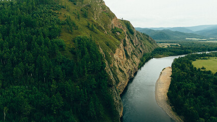 A tranquil river winding through rocky cliffs and dense forests, creating a breathtaking natural...