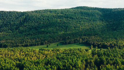 Fototapeta premium A river winding through mountains in Zakamensky District, Buryatia. Majestic peaks and serene natural beauty.