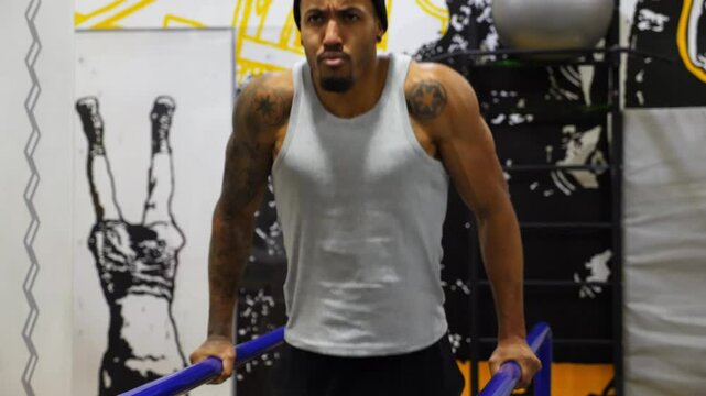 Strong african athlete doing push ups on parallel bars at sport club. Muscular afro american sportsman with tattoos doing hard exercises modern gym. Concept of healthy and active lifestyle. Slow mo