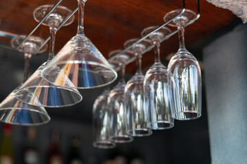 A row of wine glasses are hanging from a rack