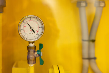 A yellow wall with a white and green valve on it. pressure gauge