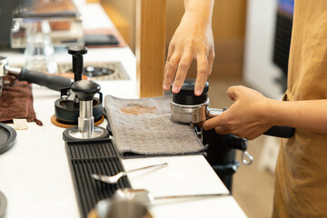 A barista is grinding coffee beans and preparing a cup of coffee