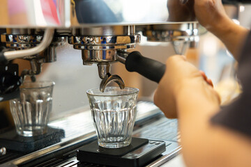 A barista is making coffee with a glass cup