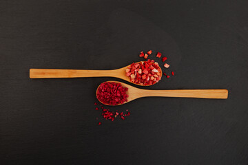 Dried freeze dried strawberries and raspberries in wooden spoons on dark background. Dehydrated...