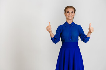 Woman in a blue dress on a white background with both hands thumbs up