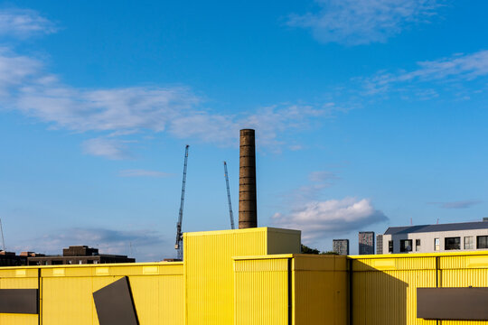 Vibrant yellow industrial buildings with geometric forms under a clear blue sky, emphasizing strong architectural design.