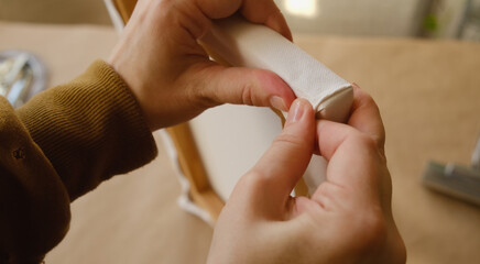 Hands stretching primed white canvas on stretcher frame.