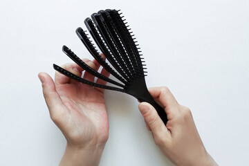 Obraz premium Black plastic movable hair comb in hand of Caucasian woman. White background.