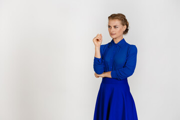 Woman in a blue dress on a white background comes up with a plan while looking off to the side