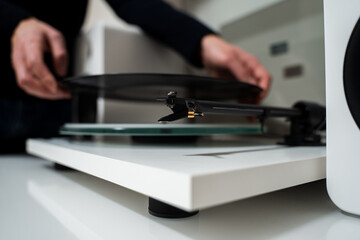 Musician hands are placing vinyl record on a turntable player. Music lover is under preparation vinyl player for playback.