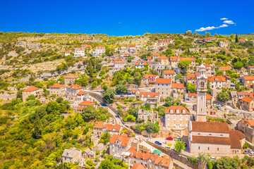 Fototapeta premium A breathtaking aerial view of Lozisca on Brac Island, Croatia, showcasing its iconic bell tower, and the surrounding Mediterranean countryside, capturing the beauty of this charming island village