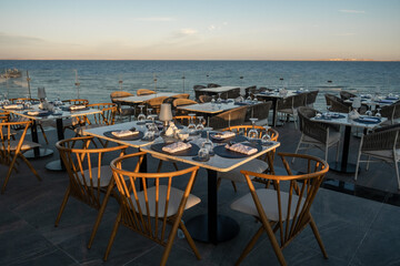Golden sunset casts a warm glow over elegantly set tables at a seaside restauran