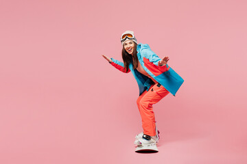 Full body side profile view young woman wears warm blue padded jacket ski goggles mask spend weekend winter season in mountains riding snowboard lean isolated on plain pink background. Hobby concept. © ViDi Studio