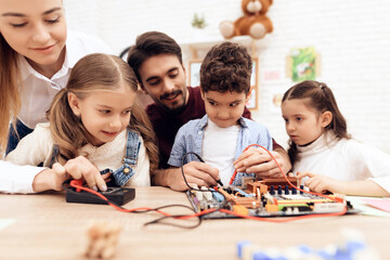 Children together with the teacher work with a soldering iron.