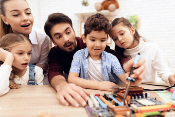 Children together with the teacher work with a soldering iron.