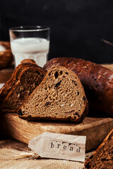rye bread with raisins, dried apricots, sunflower seeds, caraway seeds, two loaves of bread on a wooden background, flour, sieve, rolling pin, eggs, homemade bread, wheat ears, black bread with butter