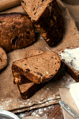 rye bread with raisins, dried apricots, sunflower seeds, caraway seeds, two loaves of bread on a wooden background, flour, sieve, rolling pin, eggs, homemade bread, wheat ears, black bread with butter