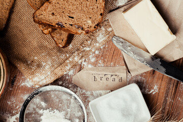 rye bread with raisins, dried apricots, sunflower seeds, caraway seeds, two loaves of bread on a wooden background, flour, sieve, rolling pin, eggs, homemade bread, wheat ears, black bread with butter