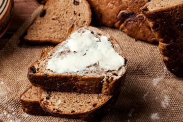 rye bread with raisins, dried apricots, sunflower seeds, caraway seeds, two loaves of bread on a wooden background, flour, sieve, rolling pin, eggs, homemade bread, wheat ears, black bread with butter
