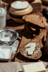 rye bread with raisins, dried apricots, sunflower seeds, caraway seeds, two loaves of bread on a wooden background, flour, sieve, rolling pin, eggs, homemade bread, wheat ears, black bread with butter