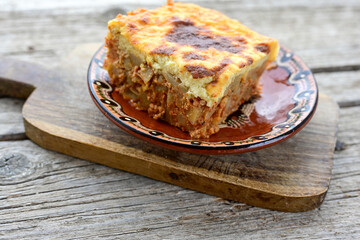  Potato and minced meat  Casserole  with   parmesan cheese and garlic on wooden rustic bakcground.  Bulgarian moussaka