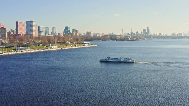 Ferry navigating Moscow river canal at Rechnoy Vokzal station with Moscow city skyline in the background