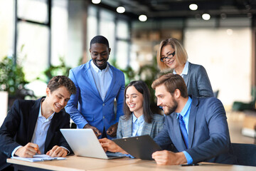 Group of young modern people in suits using modern technologies while working in the creative office.