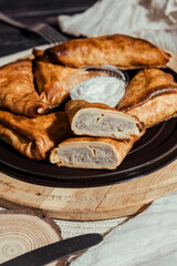 benderyki with sour cream on a wooden plate, flatlay, pancakes with meat in batter, Ukrainian...