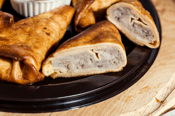 benderyki with sour cream on a wooden plate, flatlay, pancakes with meat in batter, Ukrainian...