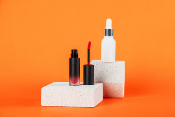 White tube and red spray on light white podiums. White blank unbranded flacons with cosmetology products. Professional concept of skin care on orange background.