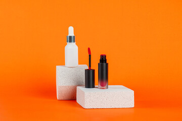 White tube and red spray on light white podiums. White blank unbranded flacons with cosmetology products. Professional concept of skin care on orange background.