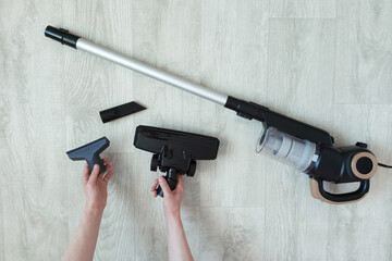 Upright vacuum cleaner and vacuum cleaner brush attachments in hands of Caucasian woman on room...