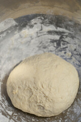 A round, raw dough sits in a metal bowl