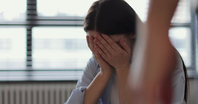 Young woman sitting on sofa, looks pessimistic and sad, almost crying, man calming her down, softly touches and hugs her. Partnership and support concept.
