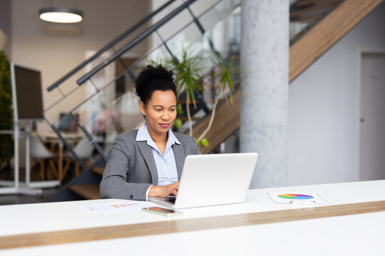 Mature African American entrepreneur multitasking with a laptop in an office