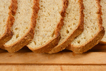 Slices of homemade bread with chia seeds are arranged on a wooden cutting board, showcasing the texture and healthy ingredients
