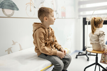 A little boy sitting at doctor office in hospital and waiting.
