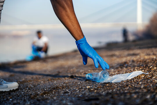 Cropped picture of diverse volunteer cleaning riverbank from plastic and paper waste on earth's day. - Powered by Adobe