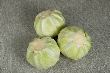 Whole heads of fresh white cabbage on a gray stone background close-up.