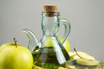 Apple cider vinegar in a glass vinegar bowl among apples