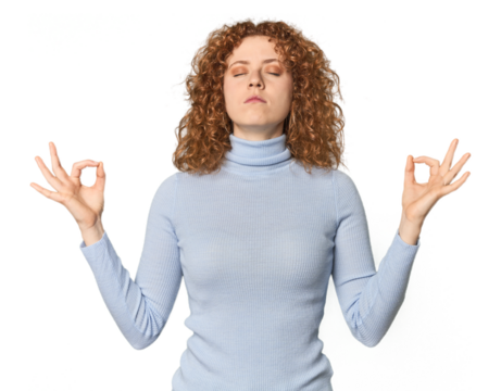 Young Caucasian redhead woman relaxes after hard working day, she is performing yoga.